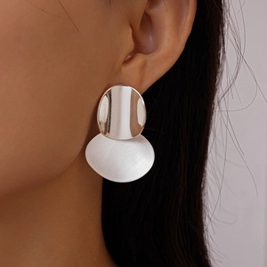 Detail of silver geometric oval earrings featuring a mix of polished and brushed metal finishes
