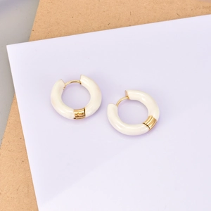 Détail des boucles d'oreilles créoles en émail blanc avec accents en acier doré