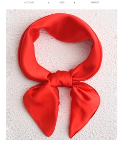 Close-up of bright red silk scarf tied in a neat bow on a textured white surface