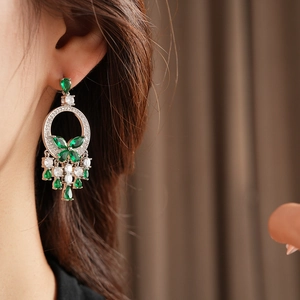 Gros plan de boucles d'oreilles émeraude avec motif papillon et pierres étincelantes