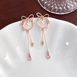 Detail of rose gold bow earrings featuring white pearls and pink teardrop crystals