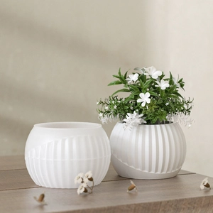 Modern white striped geometric resin planter shown with green plants on a wooden table