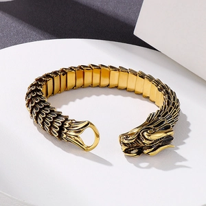 Retro golden dragon scale bracelet with intricate dragon head carving on white pedestal