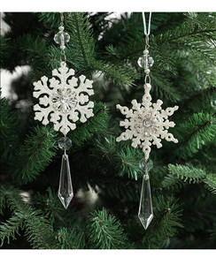 Detail of glittery silver snowflake ornaments with clear acrylic beads on a green tree