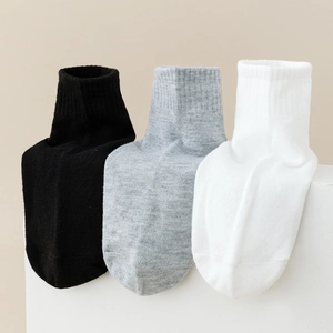 Three pairs of anti-slip cotton knit baby socks in black, grey, and white on stone