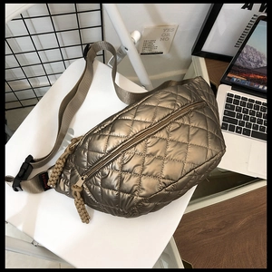 Detail of bronze quilted chest bag featuring shiny nylon texture and woven zipper pull