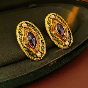 Macro shot of vintage gold oval earrings with purple stones and pearl details