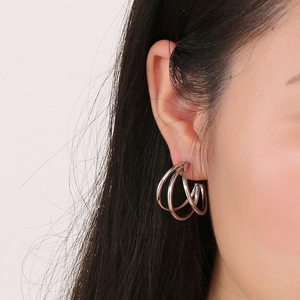 Detail of multi-layered silver C-shaped hoop earrings worn by a model in close-up shot