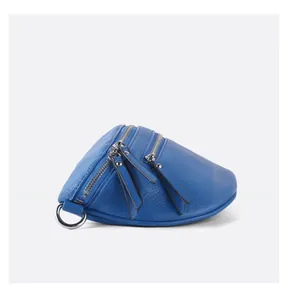 Detail of blue pebble grain leather bag featuring three silver zippers and metal D-ring