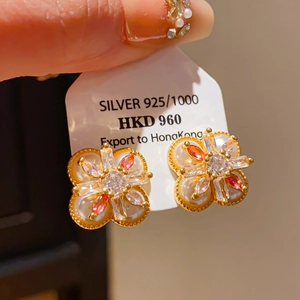 Gros plan détaillé d'une boucle d'oreille fleur en or avec perles et zircons colorés