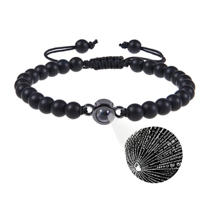 Detail eines mattschwarzen Perlenarmbands mit I Love You Projektion und gewebtem Band