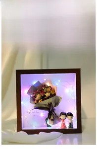 Detail view of wooden shadow box with dried flowers, LED lights and cute couple figurines