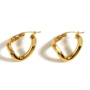 Detailed view of polished wavy irregular gold-plated hoop earrings on a white background