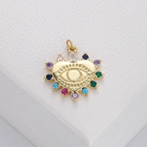 Macro shot of gold-plated evil eye charm with colorful embedded gemstones and teardrop crystals