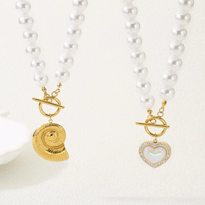 Close-up of pearl necklaces featuring golden seashell and heart pendants with OT clasps