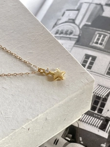 Detail of gold star pendant with hammered texture and zircon on minimalist chain