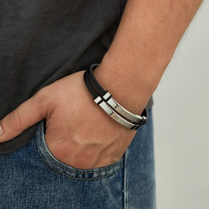 Close-up of double-layer black braided leather bracelet with silver metal clasp on wrist