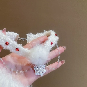 Détail du ras de cou de Noël en fourrure blanche avec strass rouge et perle flocon