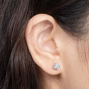 Close-up of classic 925 sterling silver four-prong stud earring on ear with round stone