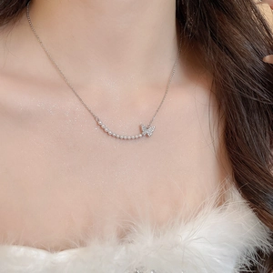 Close-up of elegant silver butterfly necklace with pearls worn on model's neck