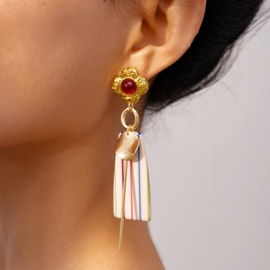 Detail of creative resin drop earrings with geometric stripes and golden metal accents