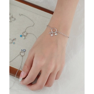 Silver charm bracelet with stars and cross pendants worn on a wrist for styling