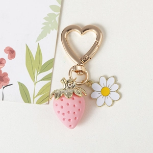 Detail of pink strawberry keychain with golden heart clasp and small white daisy charm