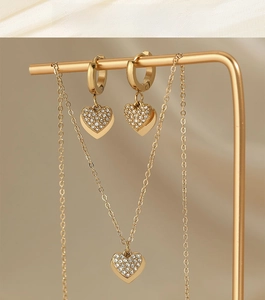 Detailed close-up of golden heart jewelry set with clear zircon on a display stand