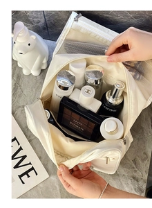 Top-down view of a spacious white travel toiletry bag organized with multiple beauty products