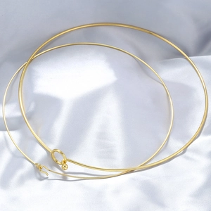 Minimalist gold stainless steel choker necklace on white satin fabric background