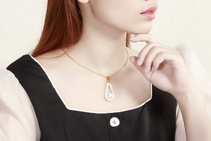 Close-up of elegant gold necklace with water-drop pearl pendant and shiny rhinestones