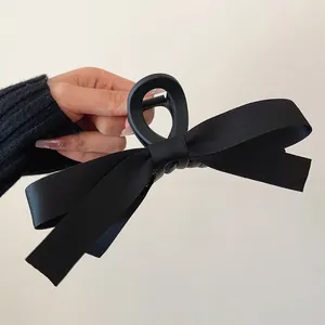 Detail of a large matte black shark clip with elegant double-layered ribbon bow