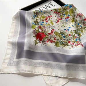 Detailed close-up of floral print silk scarf with colorful patterns on white base