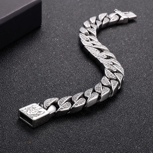 Macro shot of iced out silver Cuban link bracelet with engraved clasp on black background