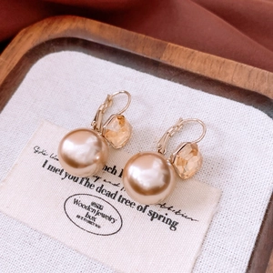 Macro shot of French vintage earrings with champagne pearls and amber crystals
