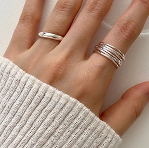 Detail of silver 925 multi-layered wrap ring and simple polished band on finger