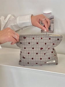 Borsa cosmetica a quadretti con pois rossi e ricamo a fiocco tenuta da modella