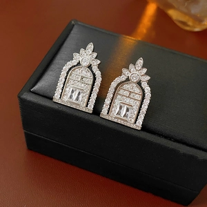 Detail of silver geometric arch earrings with cubic zirconia on black leather case