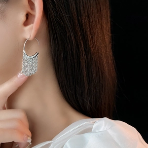 Silver C-shaped tassel earrings on model featuring elegant dangling thin metal chains