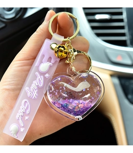 Detail of purple quicksand heart keychain with liquid glitter and golden bell