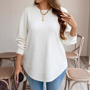 Detailed view of white waffle knit sweatshirt featuring a unique curved hemline design