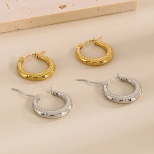 Dettaglio macro di orecchini a cerchio stile croissant oro e argento su pietra