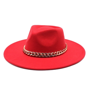Close-up of a vibrant red fedora hat with a bold gold chain band detail on a white background