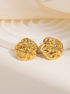 Detail of gold geometric earrings with irregular organic texture on white wave stand