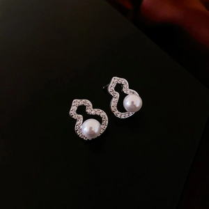 Macro shot of silver gourd-shaped earrings with zircon pavé and large round pearls