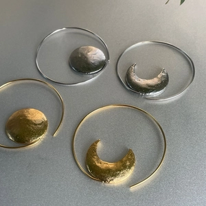Detail of creative gold and silver sun moon earrings with handcrafted hammered texture