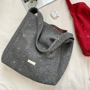 Vista piatta di una borsa tote in lana grigia con stelle e targhetta per lo stile invernale