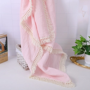 Close-up of pink muslin cotton baby blanket featuring delicate lace tassel edge