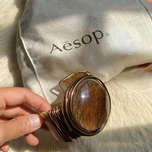 Macro shot of handcrafted gold wire-wrapped cuff bracelet featuring a large brown gemstone