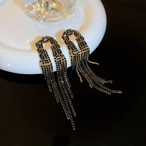 Gothic style tassel earrings with black rhinestones and gold chains on a white base